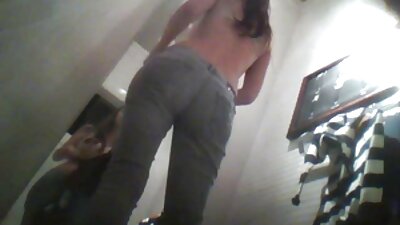 O brunetă cu sâni mici călărește un cocoș pe patul din cameră